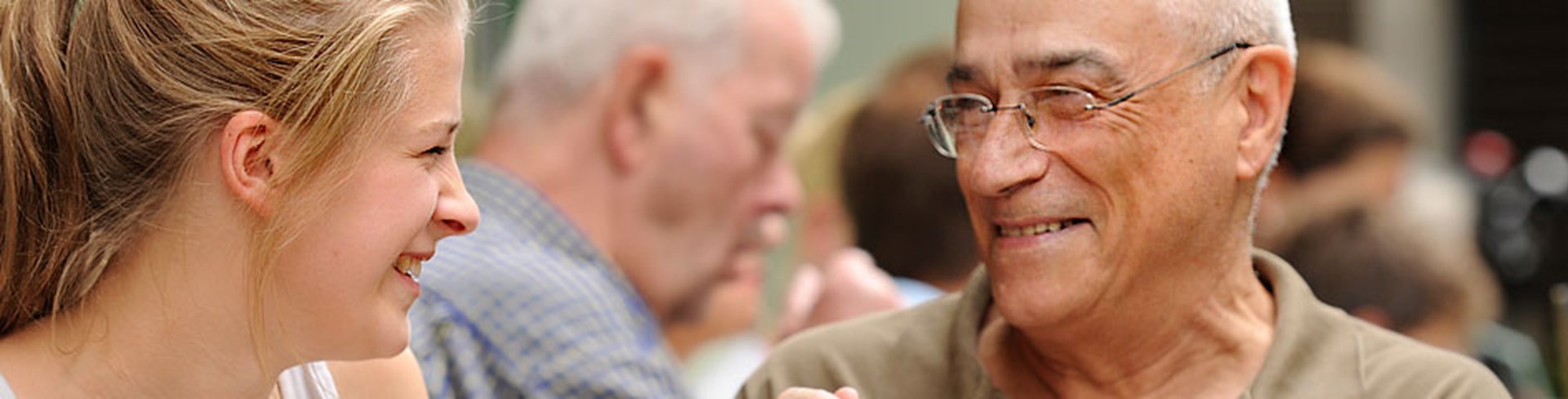 Junge Frau und älterer Herr lächeln sich an